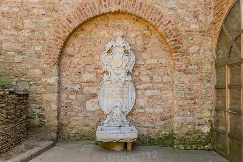 Water fountain with broken taps in shape of coat of arms against brick wall in Istanbul, Tuerkiye