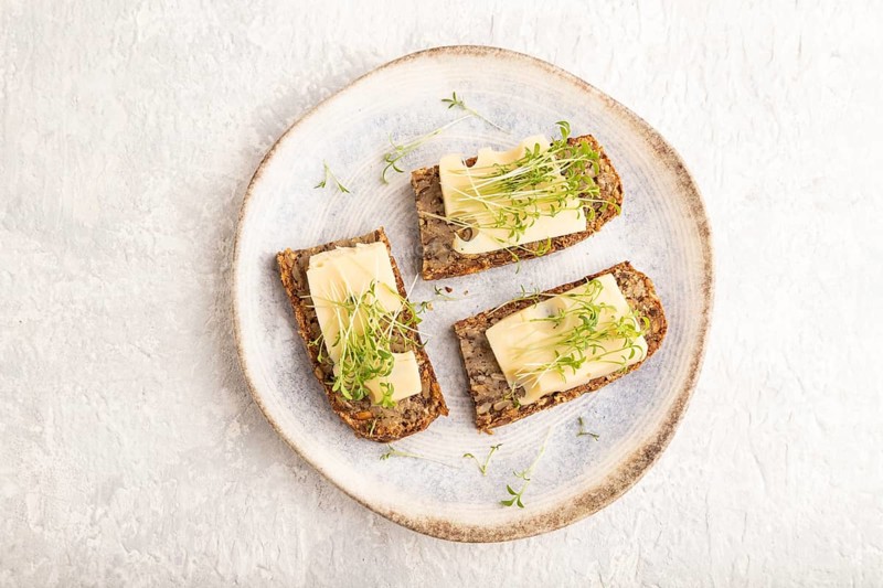 Grain bread sandwiches with cheese and watercress microgreen on gray concrete background. top view, flat lay, close up