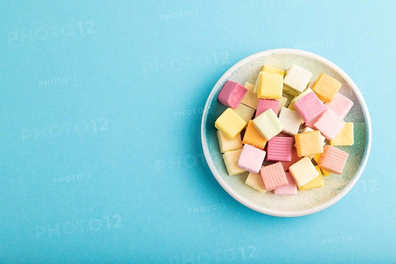Various fruit jelly chewing candies on plate on blue pastel background. apple, banana, tangerine, top view, flat lay, copy space