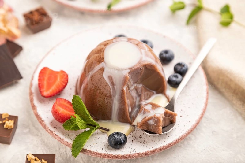 Chocolate jelly with strawberry, blueberry and milk cream sliced with spoon on gray concrete background and linen textile. side view, close up, selective focus