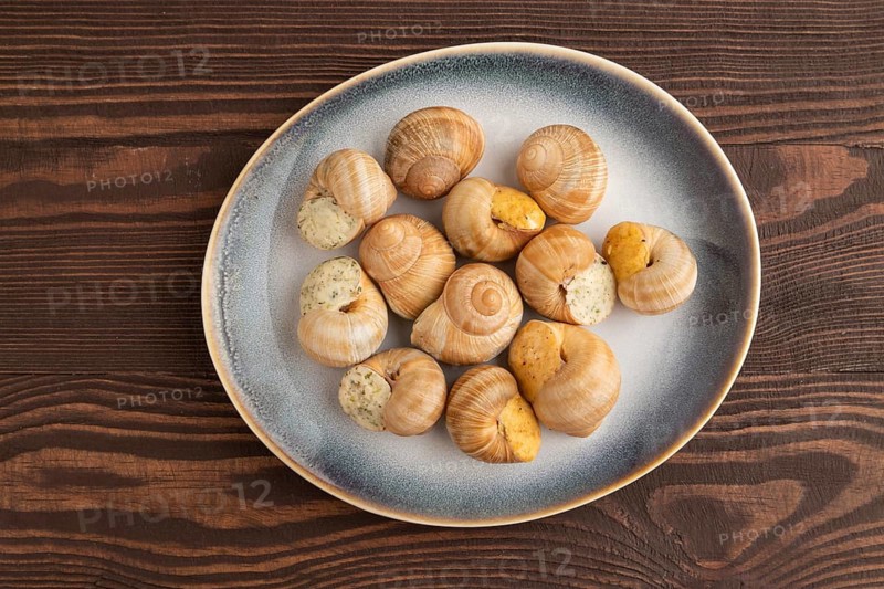 Grape (Burgundy) snails with butter and cheese on brown wooden background. Top view, flat lay