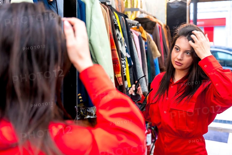 Woman looking in the mirror while shopping in a second hand store