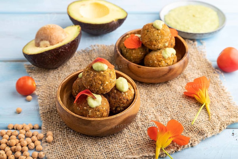 Falafel with guacamole on blue wooden background and linen textile. Side view, close up