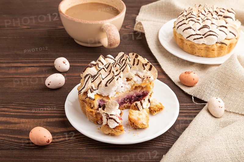 Tartlets with meringue cream and cup of coffee on brown wooden background and linen textile. side view. Breakfast, morning, concept
