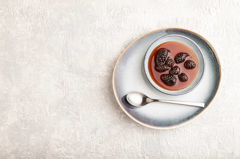 Pine cone jam on ceramic plate on gray concrete background. Top view, flat lay, copy space