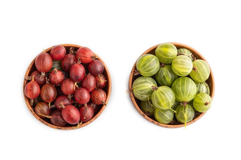 Fresh red and green gooseberry in clay bowl isolated on white background. top view, flat lay, close up