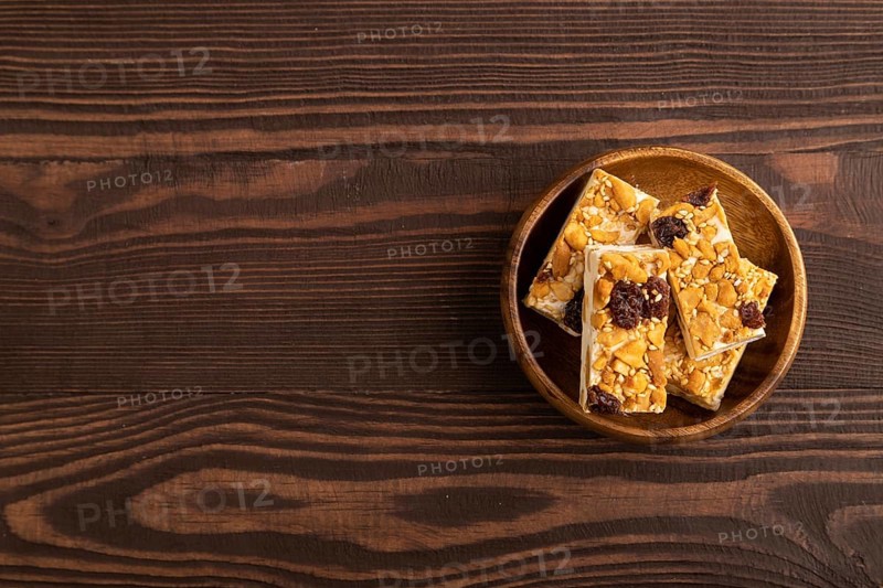 Traditional candy nougat with nuts and sesame on brown wooden background. top view, flat lay, copy space