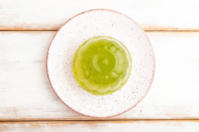 Mint green jelly on white wooden background. top view, flat lay, close up