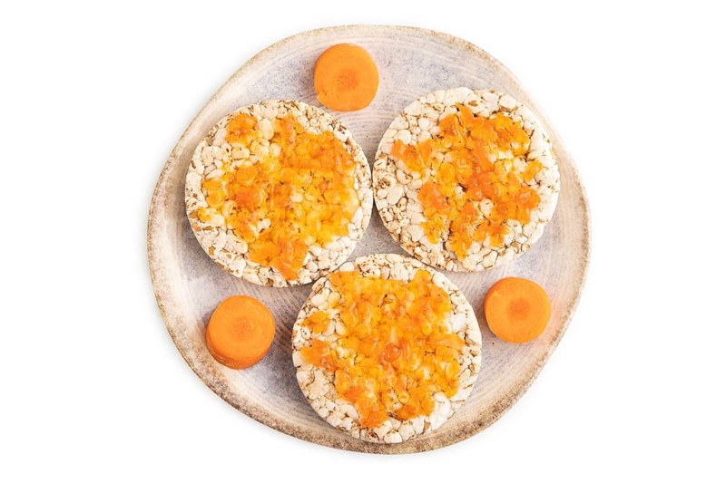 Carrot jam with puffed rice cakes isolated on white background. Top view, flat lay, close up