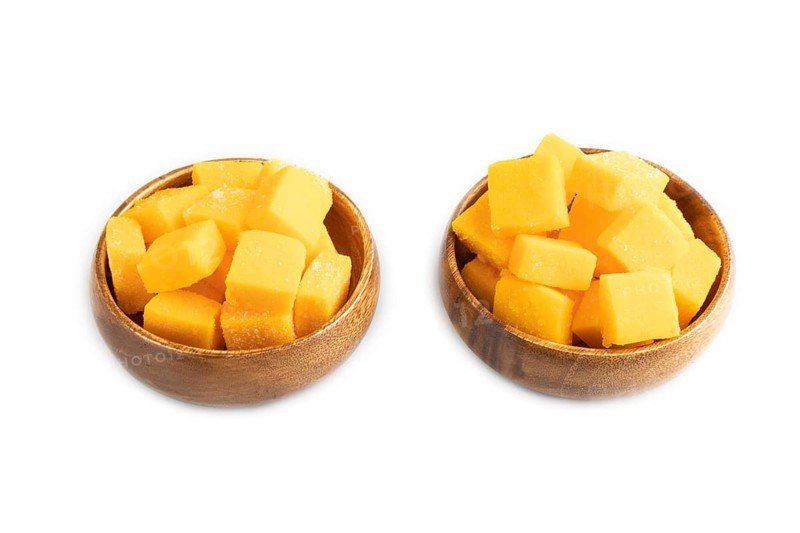 Dried and candied mango cubes in wooden bowls isolated on white background. Side view, close up, vegan, vegetarian food concept