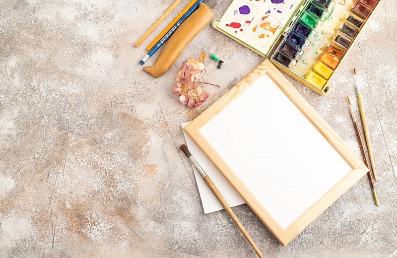 Drawing accessories set: brushes, pencils, watercolor, frame on brown concrete background. Top view, flat lay, copy space