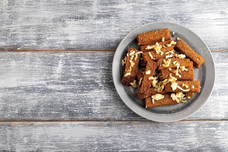 Cheese and toast on a gray plate on a gray wooden background. Top view, flat lay, close up, copy space