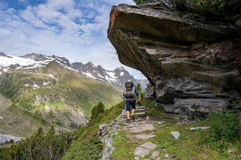 Mountaineer on a hiking trail under a rocky outcrop in a picturesque mountain landscape, Berliner Hoehenweg, Zillertal Alps, Tyrol, Austria, Europe
