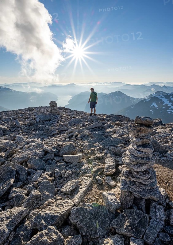 Mountaineer on the summit of Skala with cairn, view of mountain landscape and fjord Faleidfjorden, Sonnenstern, Loen, Norway, Europe