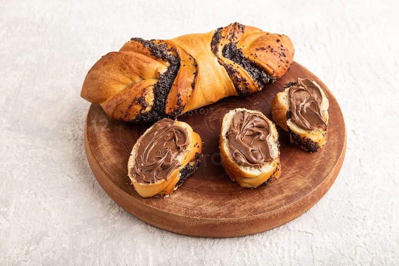 Homemade sweet bun with chocolate cream on a gray concrete background. side view, close up