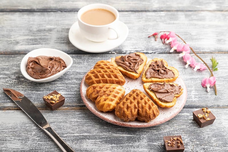 Homemade waffle with chocolate butter and cup of coffee on a gray wooden background. side view, close up