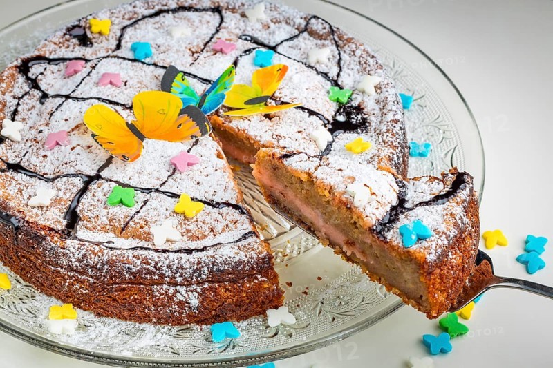 Succulent cake with butterfly decoration and colourful sprinkles on a glass plate, white base