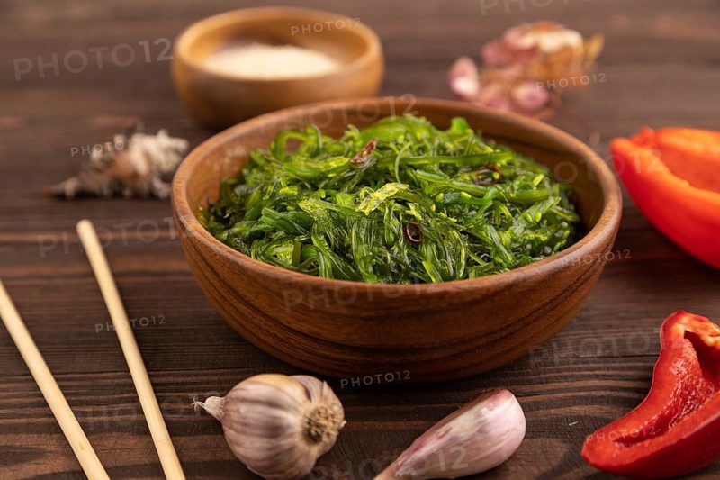 Chuka seaweed salad in wooden bowl on brown wooden background. Side view, close up, selective focus