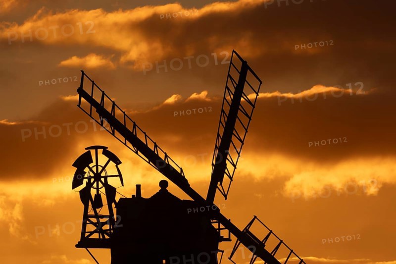Windmill silhouetted at sunset with a red sky and clouds behind, Cley-next-to-the-sea, Norfolk, England, United Kingdom, Europe