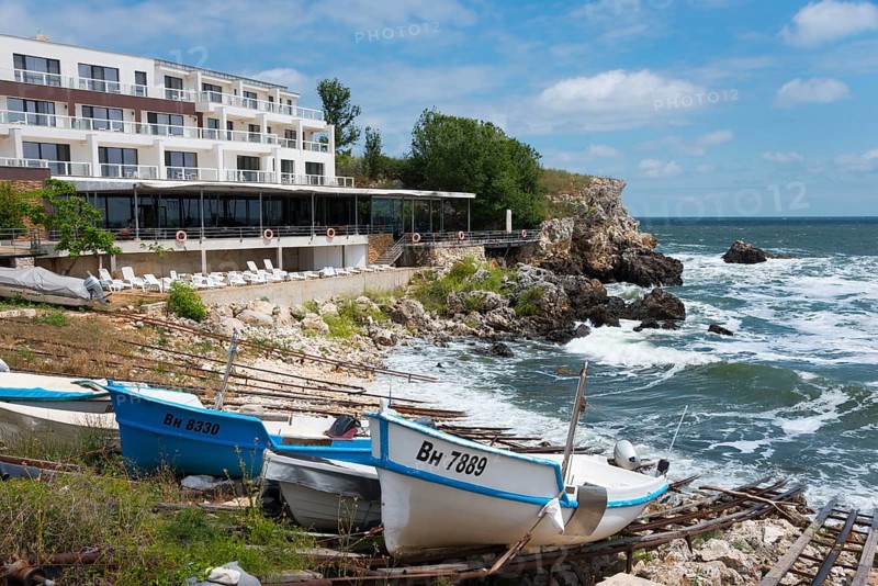 A coastal hotel overlooking the moving sea, surrounded by boats and rocky landscape, harbour and hotel, Tyulenovo, Shabla, Dobrich, Black Sea, Bulgaria, Europe