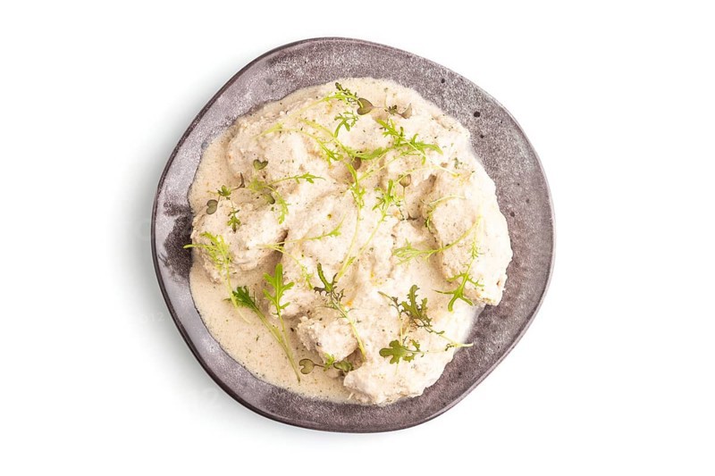 Stewed chicken fillets with coconut milk sauce and mizuna cabbage microgreen isolated on white background. top view, flat lay, close up
