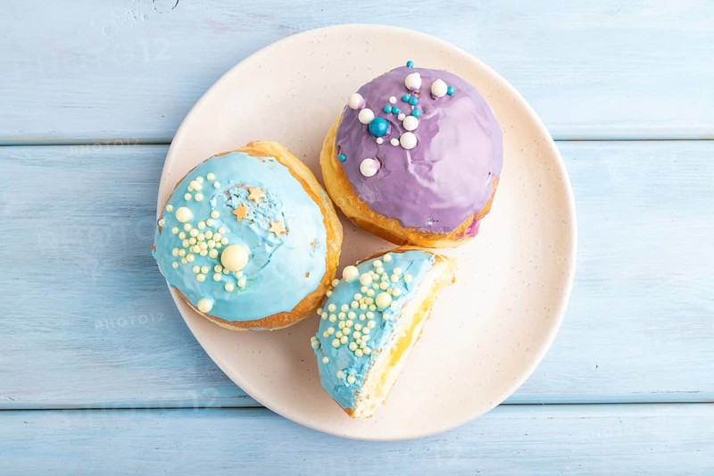Purple and blue glazed donut on blue wooden background. top view, flat lay. Breakfast, morning, concept