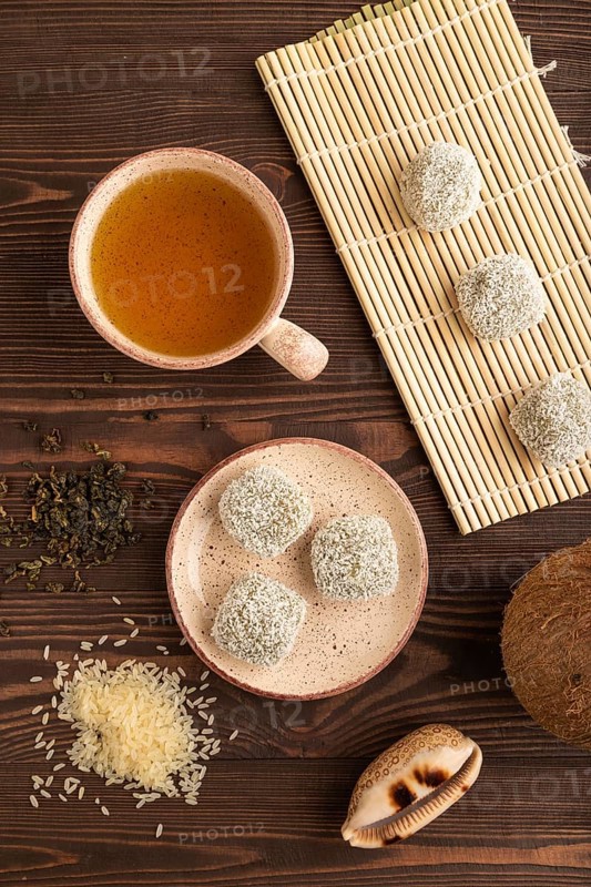 Japanese rice sweet buns mochi filled with pandan and coconut jam and cup of green tea on brown wooden background. top view, flat lay, close up