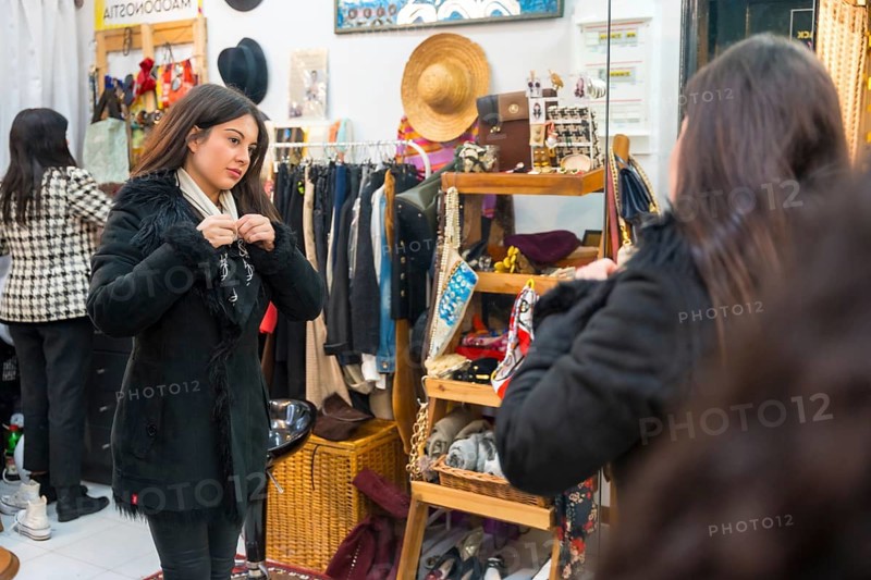 Young and beauty woman trying on a jacket in a clothing store during sales
