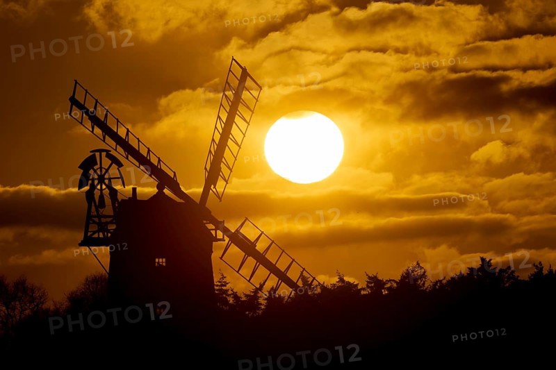 Windmill silhouetted at sunset with a red sky and clouds behind, Cley-next-to-the-sea, Norfolk, England, United Kingdom, Europe