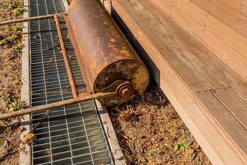 Hand pushed surface roller in front of wooden stadium benches at edge of dirt field