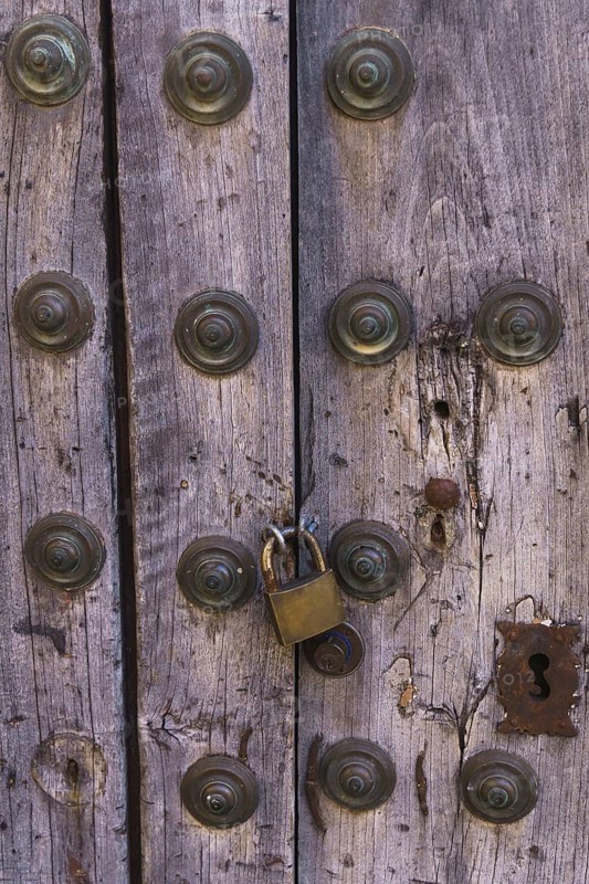 Antique wooden door with metal rivets and a padlock