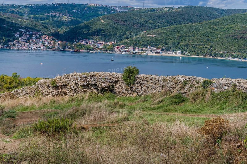 Remains of castle wall ruins with Bosphorus Strait and coastal village in background in Istanbul, Tuerkiye