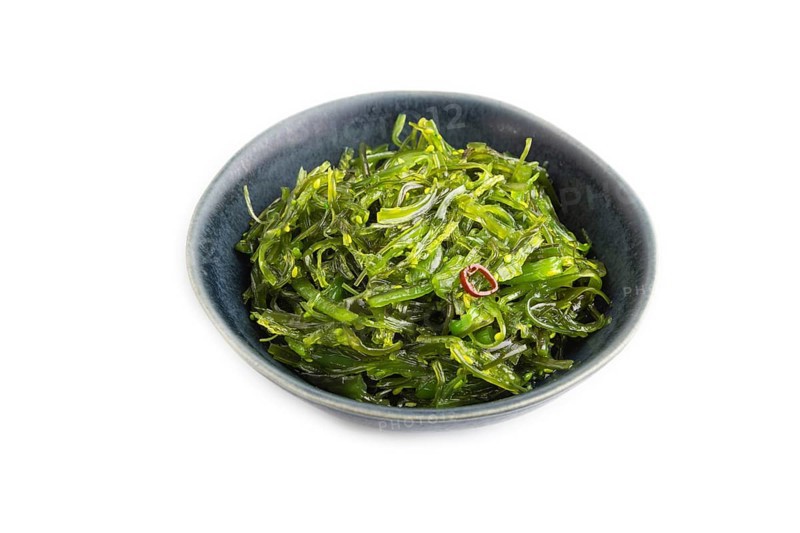 Chuka seaweed salad in blue ceramic bowl isolated on white background. Side view