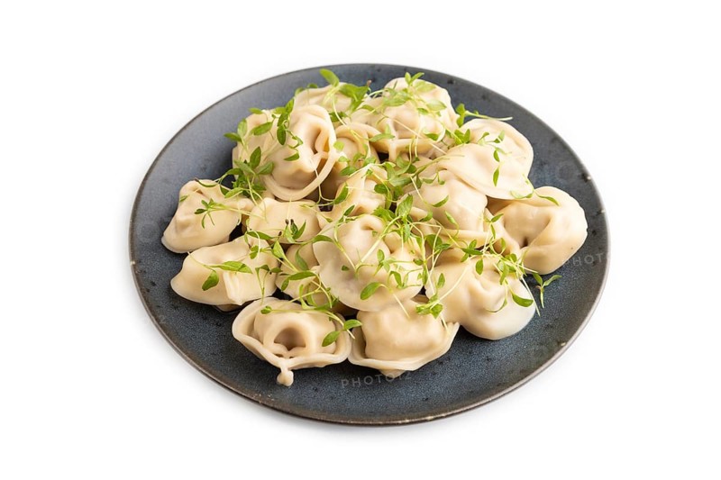 Dumplings with pepper, salt, herbs, microgreen isolated on white background. Side view, close up
