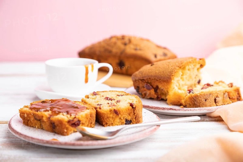 Homemade cake with raisins, almonds, soft caramel on a white and pink background. Side view, close up, selective focus