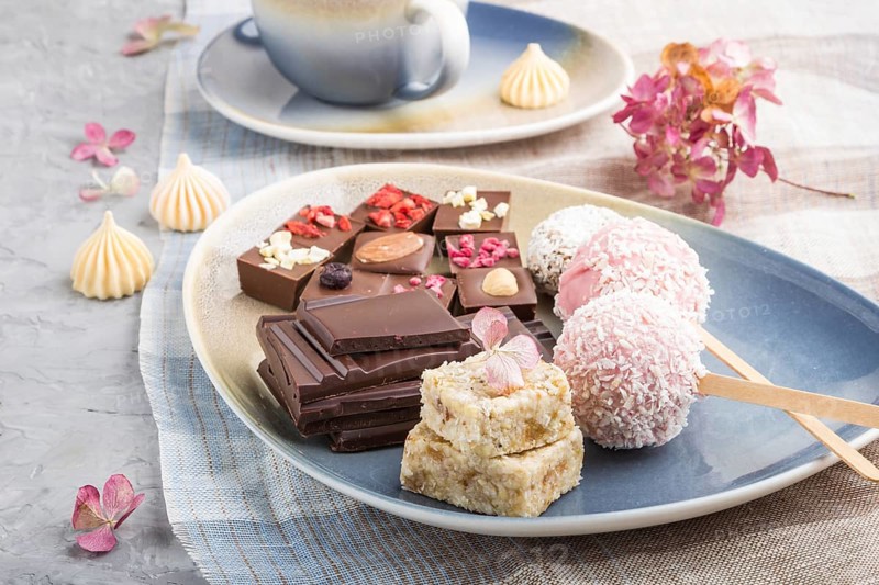 A pieces of homemade chocolate with coconut candies on a blue and brown textile. side view, close up, selective focus