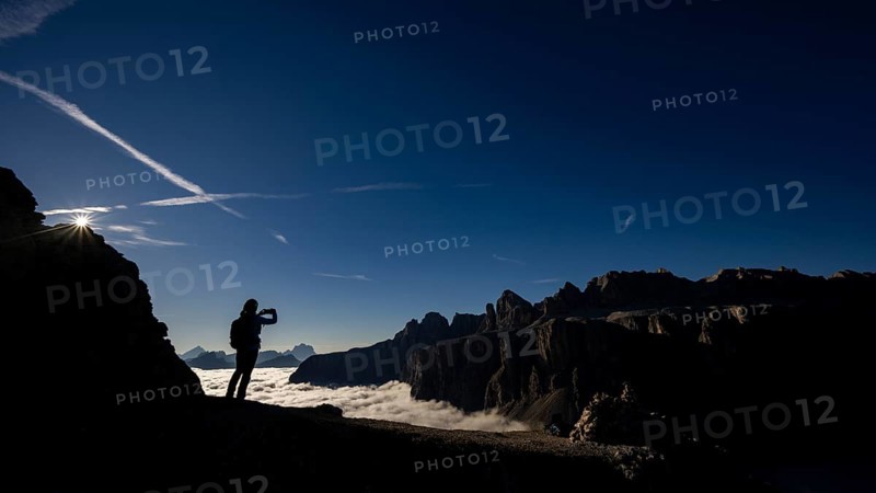 Mobile phone photographer on ridge with Dolomites mountains in the background, Corvara, Dolomites, Italy, Europe