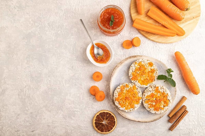 Carrot jam with puffed rice cakes on gray concrete background. Top view, flat lay, copy space