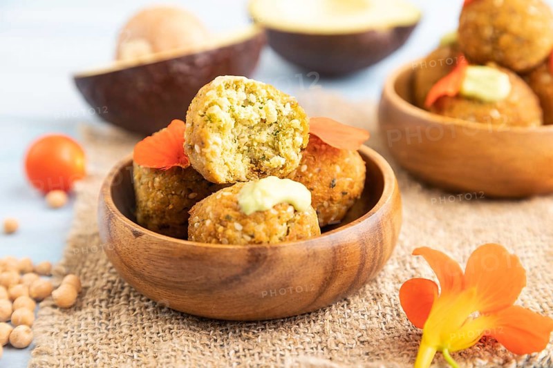 Falafel with guacamole on blue wooden background and linen textile. Side view, close up, selective focus