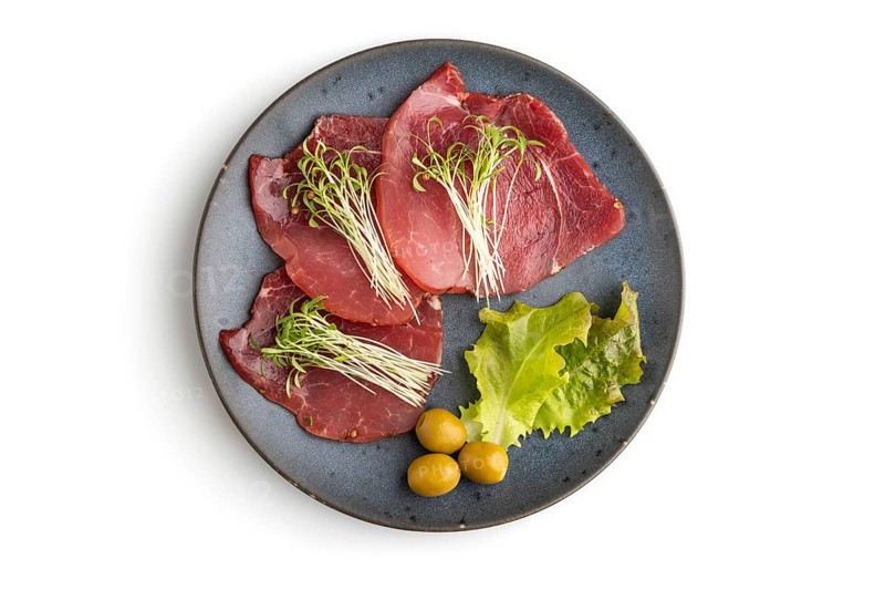 Slices of smoked salted meat with cilantro microgreen isolated on white background. Top view, flat lay, close up