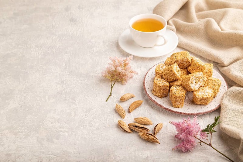 Traditional turkish delight (rahat lokum) with cup of green tea on a gray concrete background and linen textile. side view, copy space