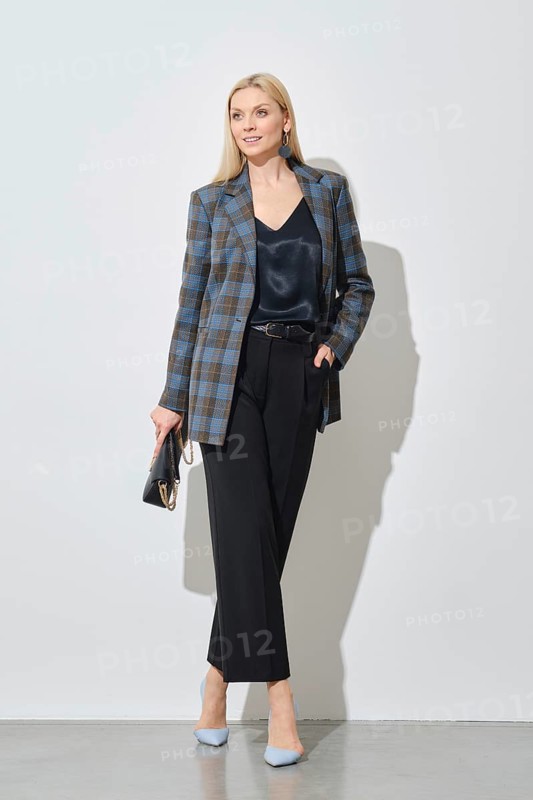 Modern businesswoman in stylish checkered jacket and loose trousers holding handbag