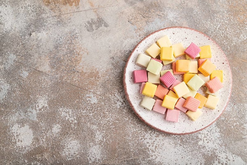Various fruit jelly chewing candies on plate on brown concrete background. apple, banana, tangerine, top view, flat lay, copy space