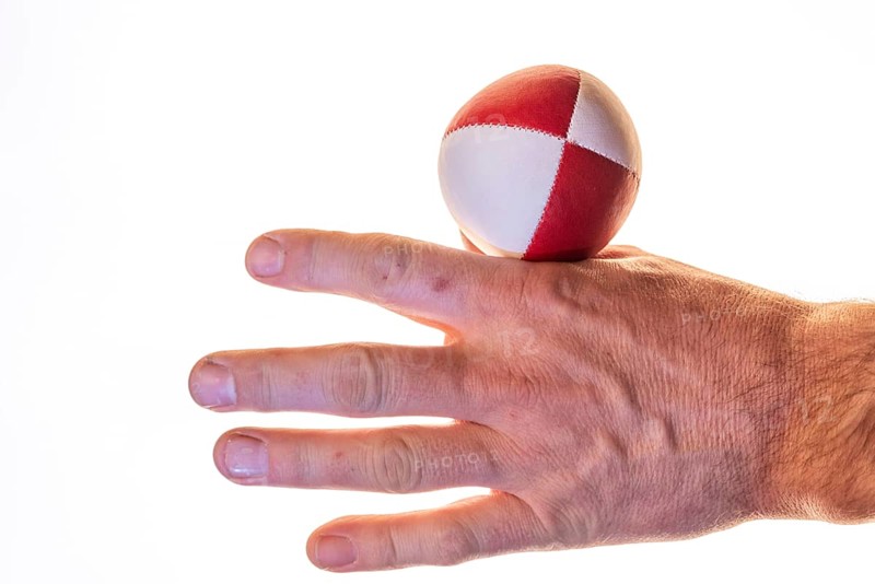 Hand with a juggling ball in front of a white background, studio shot, Germany, Europe