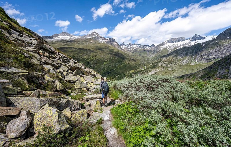 Mountaineers on a hiking trail in front of a picturesque mountain landscape, rocky mountain peaks with snow, valley Zemmgrund with Zemmbach, mountain panorama with summit Zsigmondyspitze and Grosser Moerchner, Berliner Hoehenweg, Zillertal Alps, Tyrol, Austria, Europe