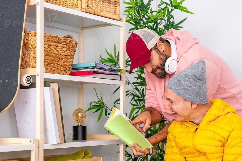 Man helping to read a book to a disabled man at home