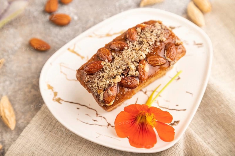 Caramel and almond cake with cup of coffee on brown concrete background and linen textile. side view, close up, selective focus