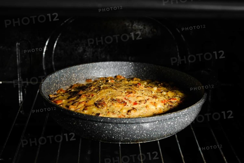 Mushroom pie with chicken meat on grid in oven