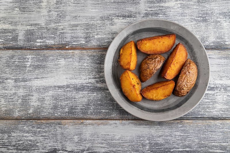 Heap of fried potato on a gray plate on a gray wooden background. Top view, flat lay, close up, copy space