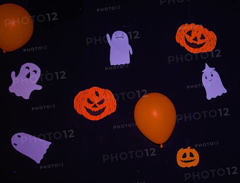 Halloween decorations of handmade ghosts, Jack-o-Lanterns, and orange balloons hanging on a black wall in South Korea